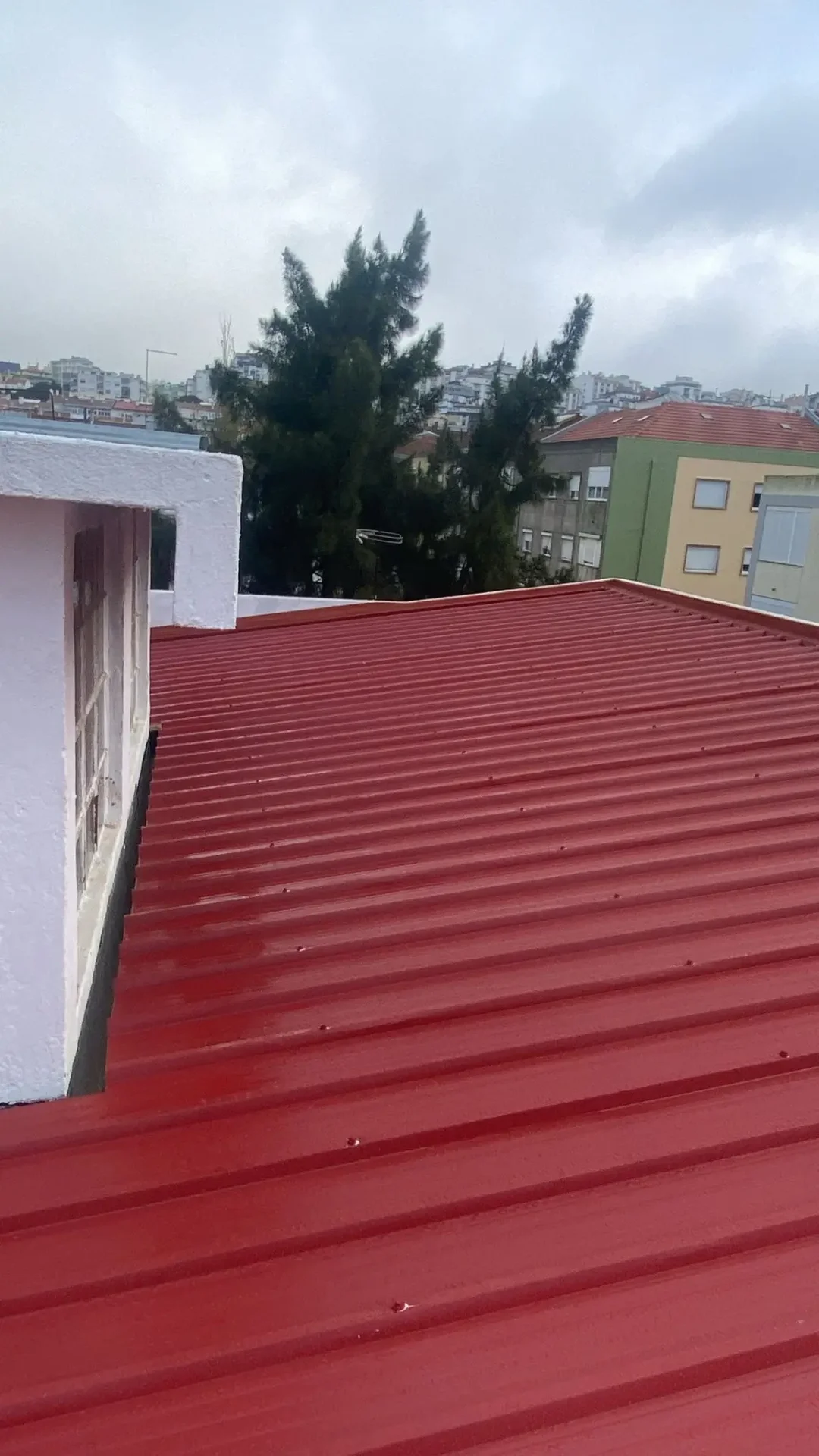 Cobertura em painel sandwich vermelho aplicada em telhado urbano, garantindo isolamento térmico e proteção em Lisboa