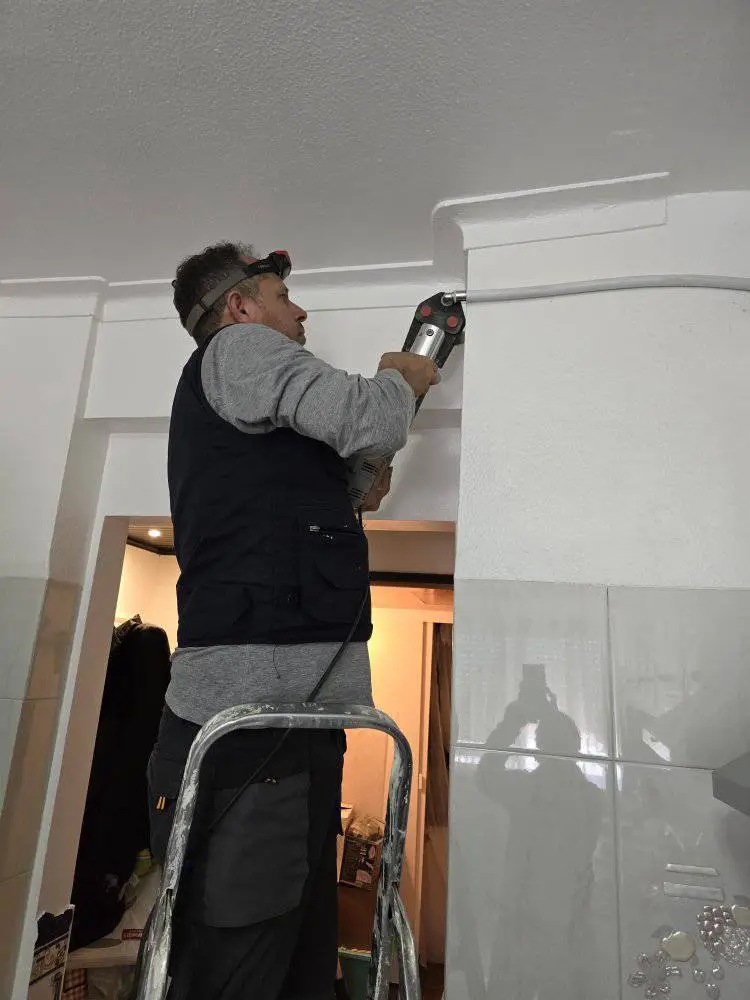 Profissional a perfurar parede para acesso a canos.