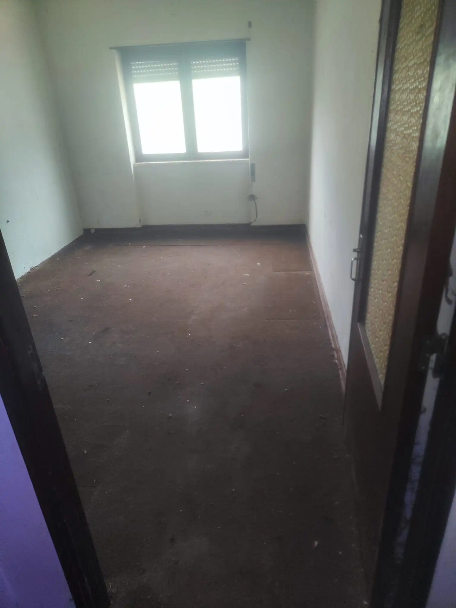 Mesmo quarto após intervenção de limpeza profunda: Chão totalmente livre permitindo circulação, paredes limpas e tratadas, superfícies sem pó com brilho restaurado e janela desobstruída com cortinas abertas.