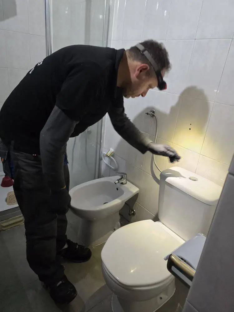 Técnico a desentupir sanita com máquina elétrica.